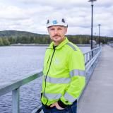Uniper Worker standing by a fence and a body of water facing the camera