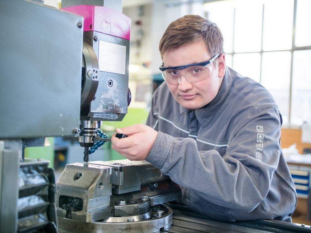 Technical apprentice with safety glass works on a machine