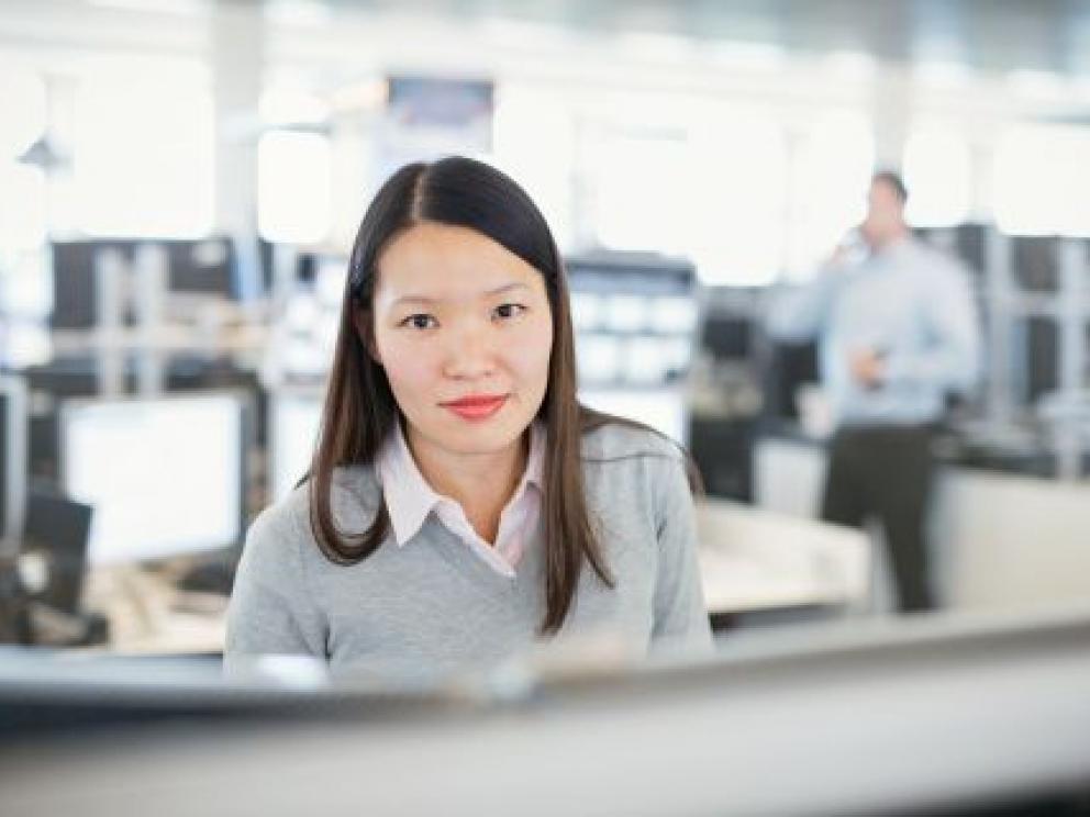 Mitarbeiterin auf dem Tradingfloor vor vielen Bildschirmen