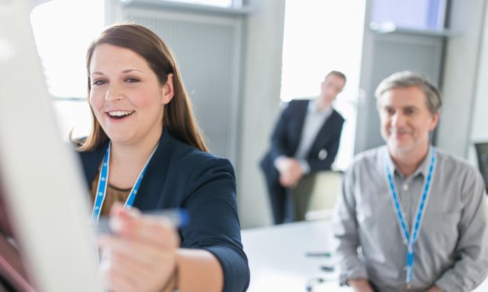 Female Uniper employee standing at a flipchart in a meeting room, two other male employees can be seen in the background