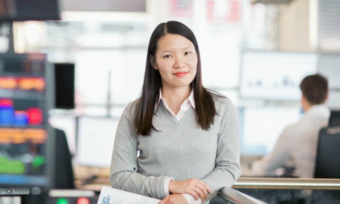 Female Uniper employee on the trading floor with many screens in the background