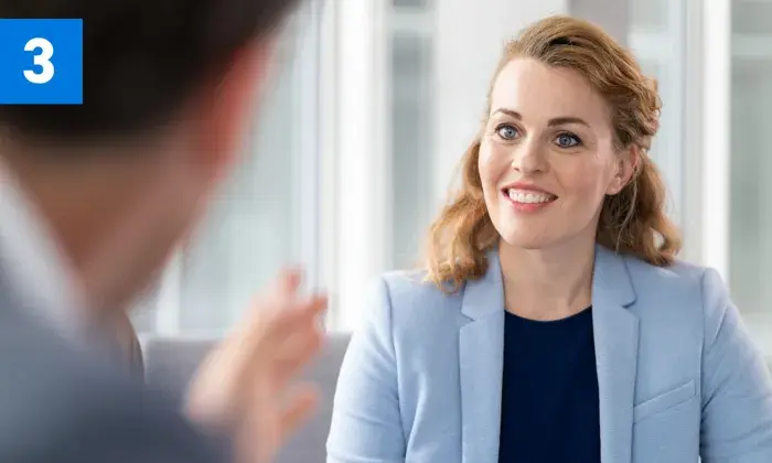 Professional woman smiling and listening during a conversation in a modern office setting.