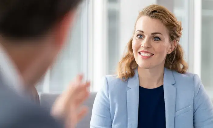 Professional woman smiling and listening during a conversation in a modern office setting.