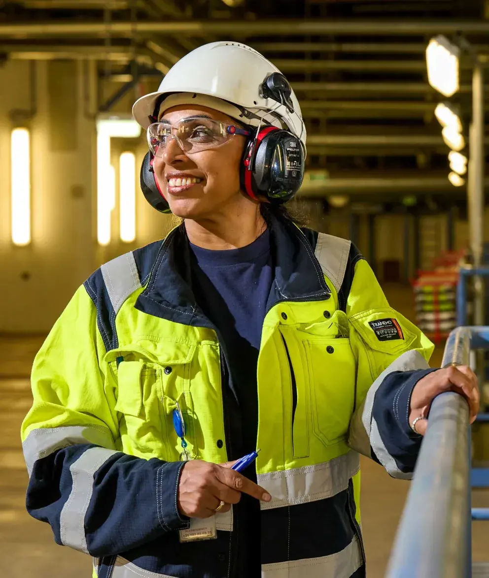 Uniper employee in safety gear smiling inside an industrial facility.