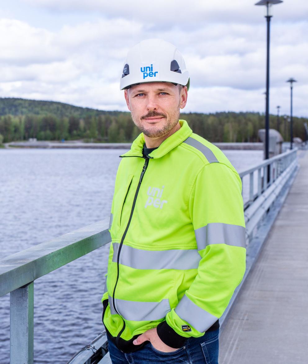 Uniper Worker standing by a fence and a body of water facing the camera