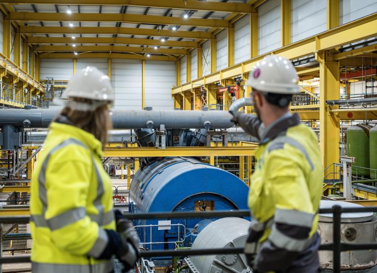 woman and man workers look at gas turbine