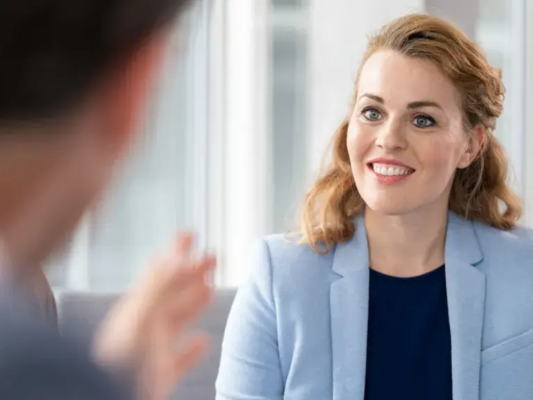 Professional woman smiling and listening during a conversation in a modern office setting.