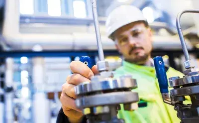 Engineer adjusting an industrial valve in a facility, focusing on maintenance and operational checks