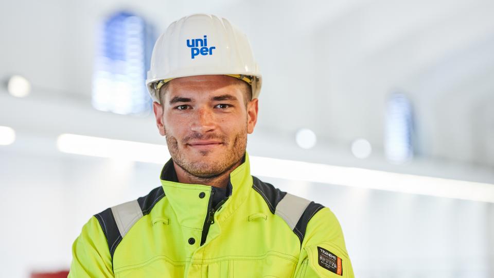 Uniper-Ingenieur mit Helm vor einem Laufwasserkraftwerk