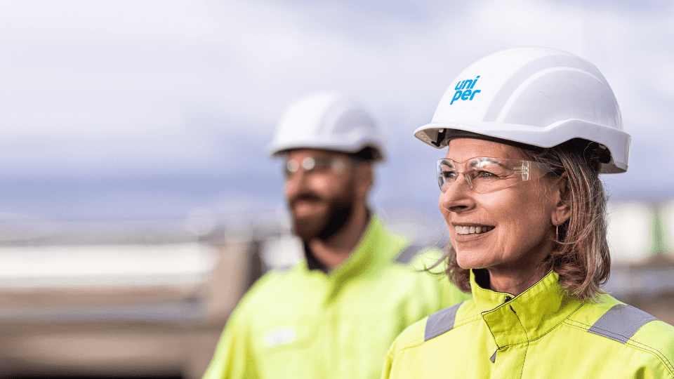 Eine weibliche und ein männlicher Uniper Mitarbeiter:in im Hintergrund mit Helmen und Sicherheitsbrille