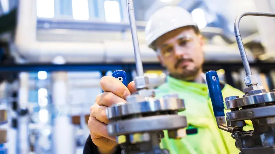 Engineer adjusting an industrial valve in a facility, focusing on maintenance and operational checks