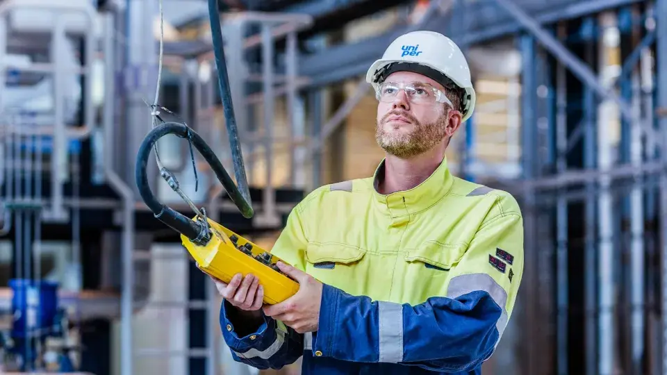 Uniper employee in safety gear operating equipment in an industrial facility.