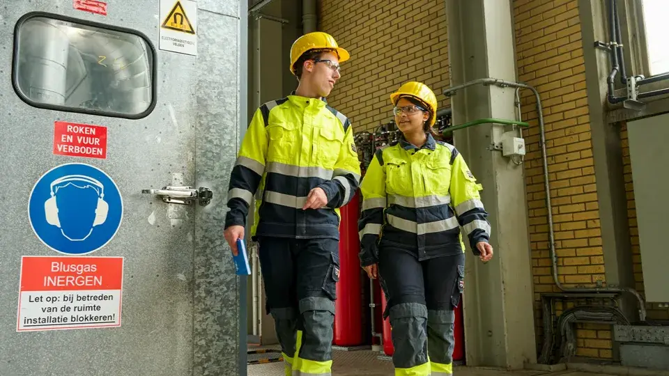 Two Uniper employees in safety gear walking together inside an industrial facility