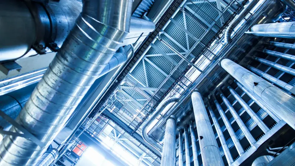 Interior view of an industrial facility with metallic pipes and infrastructure, representing energy storage and smart grid technologies.