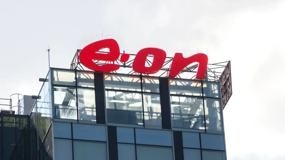 The E.ON logo displayed on the top of a modern glass building, with a cloudy sky in the background.