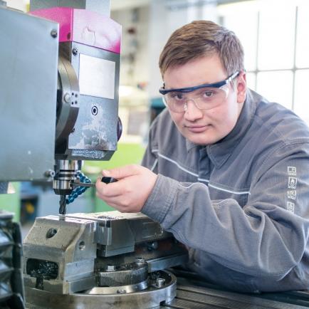 Technischer Auszubildender mit Sicherheitsglas arbeitet an einer Maschine