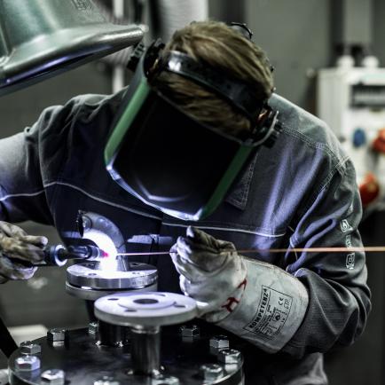 Technischer Auszubildender mit Schweißmaske beim Schweissen in der Werkstatt