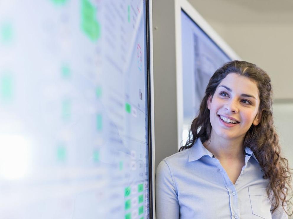 Female Uniper Apprentice smiling standing next to a big screen