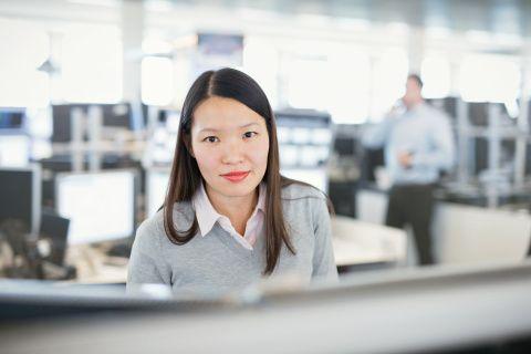 Female employee on the trading floor in front of many screens