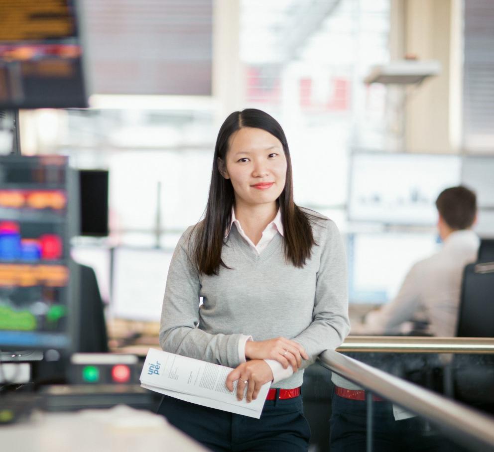 Female Uniper employee on the trading floor with many screens in the background
