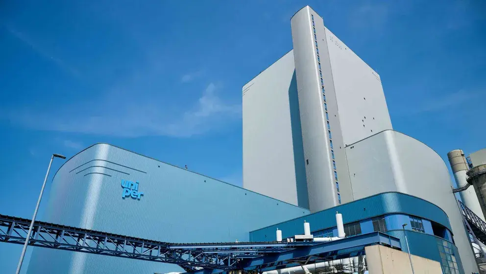 Exterior view of the MPP3 power plant at Uniper's Maasvlakte Energy Hub, featuring modern blue and white industrial architecture against a clear blue sky.